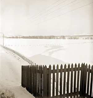 Fence Prints: A train billowing steam casts a shadow on the first mantle of snow as it travels