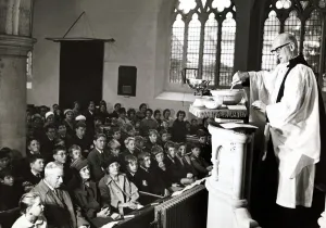 00202 Prints: Unusual - A vicar prepares his christmas pudding at a service in church