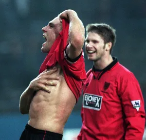 Passionate Prints: Vinnie Jones celebrates by lifting his shirt and putting his hand across his chest after