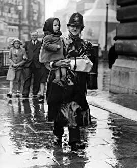 VJ Day, a policeman carries a lost child in Trafalgar Square, London. 15th August 1945
