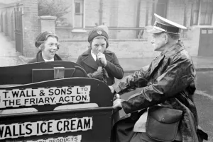 Walls Ice Cream man seen here on his tricycle serving two schoolgirls Circa