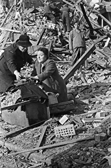 A warden helps a survivor retrieve belongings from the rubble that was her home before it