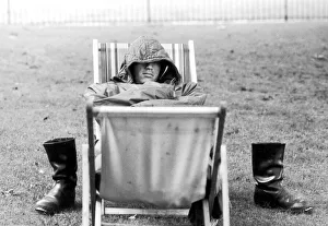 Tired Prints: A weary traveller removes his boots as he takes a rest on a bed made from two deckchairs