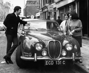 Welsh singing star Tom Jones shows off his new Jaguar car to three young fans in London