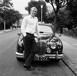 West Ham United captain Bobby Moore pictured standing beside his Jaguar car at home in