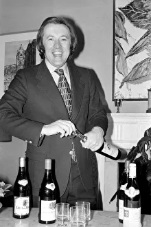 Wine: Mr. David Frost trying to open a bottle of wine at his home