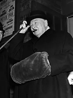 Winston Churchill wearing a hand muff as he leaves the Scala theatre in London where he