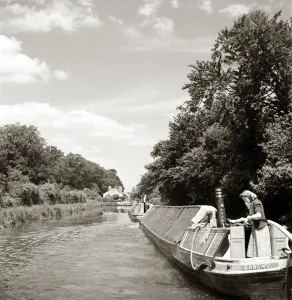 Tranquil Prints: Woman on canal boat in the sun whilst child sunbathes behind her - circa 1950