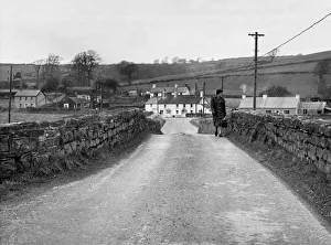 Places Prints: A woman crossing the bridge the village of Llangendeirne in the River Gwendraeth river