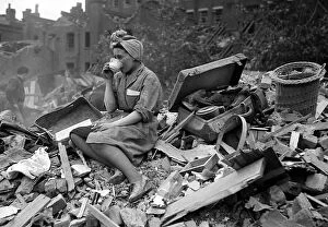 Damage Collection: A woman enjoys a cup of tea in the midst of the bomb damage at New Cross after air raids