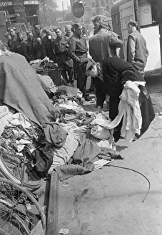 00073 Prints: A woman laying down spare clothes at a collection point to be used for others who need
