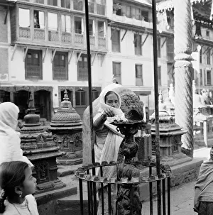 Buddhism Prints: A woman pilgrim seen here lighting candles at a Buddhist Stupa temple in Kathmandu in