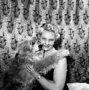 Woman showing affection to her pet dog: 1957