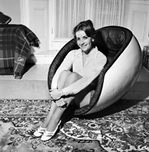 Woman sitting in an egg chair wearing white blouse and black skirt