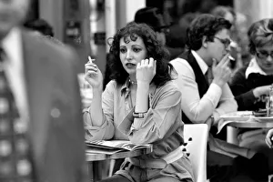 Woman sitting down smoking a cigarette at a cafe in Paris, France