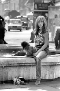 Woman stops at a fountain to rest her tired feet after walking her dog around the Kings