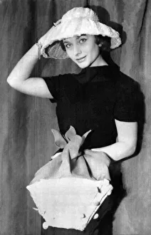 Woman wearing a black dress and hat holding a shopping bag January 1955