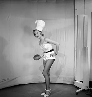 Woman wearing chefs hat holding loaf of bread. 1959 E61-004