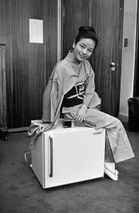 Traditional Prints: A woman wearing a Kimono sitting on a Japanese food freezer. 26th July 1965