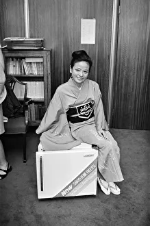 01159 Prints: A woman wearing a Kimono sitting on a Japanese food freezer. 26th July 1965