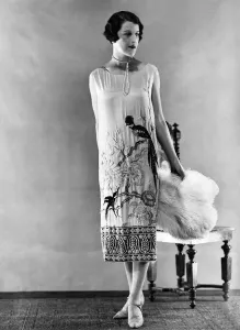 00038 Prints: Woman wearing long sleeveless dress with black parrot design at hem