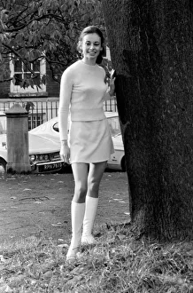 Woman wearing matching top, mini skirt and knee high looks poses for pictures