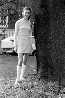 Woman wearing matching top, mini skirt and knee high looks poses for pictures