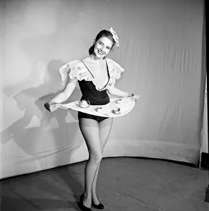 Woman wearing a skirt that is also a tray, seen here with tea pot and cups on the tray