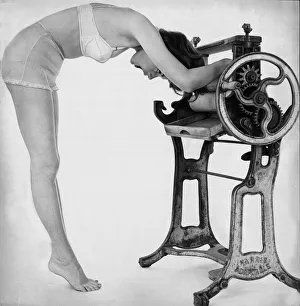 A woman wearing underwear drying her through an old fashioned roller machine