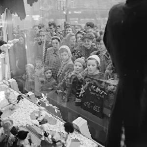 Stores Prints: Women and children looking through Sefridges shop window on Oxford Street, London