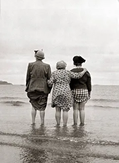 Holiday Prints: Three women look out to sea watching a ship disappear over the horizon clutching the hems