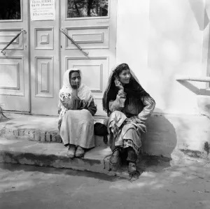 00082 Prints: Two women sitting on the steps of a shop watch the May Day parade in the Russian town of