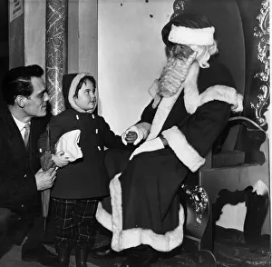 Wonderment in her eyes a young visitor as she gazes up at Santa Claus in Lewis