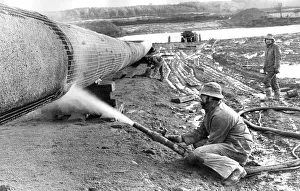 A workman sprays on the gas pipelines concrete coat in December 1974