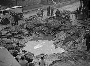 Workmen Prints: Workmen pump out a flooded bomb crater in the centre of Birmingham following an air raid