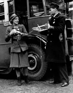Knitting Prints: World War II Women. A lady conductor of London Transport makes use of her driver during a