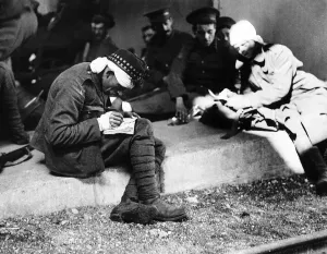 Wounded Prints: World War One - A wounded British soldier sitting on steps with comrades writes home