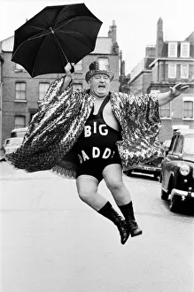 Wrestler Shirley Crabtree alias Big Daddy jumps in the air with an umbrella
