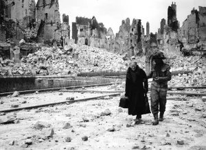 00154 Prints: WW2 Invasion of Caen in France A soldier helps an elderly woman through