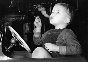 Health Prints: Three year old David Fellows, puffs away happily in his pedal-car, on a man-sized cigar
