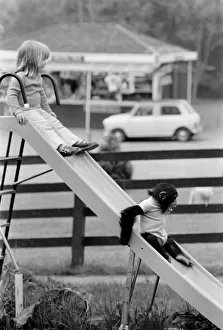 Slide Prints: Three year old Emma Colbourne playing on the slide in her local park with a chimpanzee