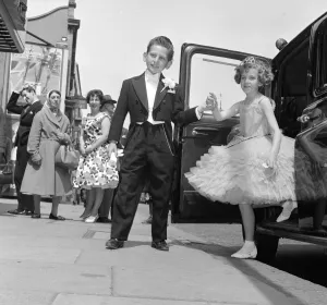 Ten year old Susan Millard wearing a crinoline style ball gown is helped out of her taxi