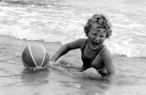 00041 Prints: Yound girl playing with her beach ball during a holiday at the seaside Circa 1945
