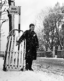 Swansea Prints: Young Andrew Burley stands in the queue for the bus with his sledge during heavy snowfall