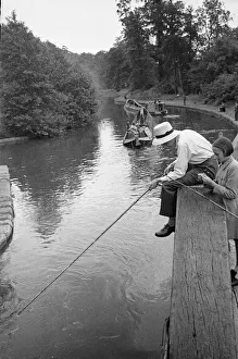 A young angler wearing a panama hat fishing in the Grand Union Canal between