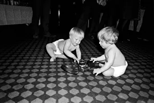Exploration Prints: Two young babies seen here examining a camera at a gathering of them parents of a West
