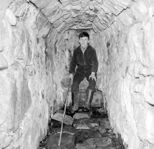 Cave Prints: A young boy poses in the Well of Heads'at Invergarry, Scotland circa 1960