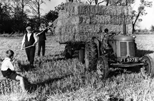 Tractor Prints: A young boy watches as farm hands load bales of straw on to the trailer at Est