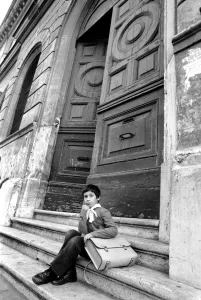 Young child sitting on the steps of an old building in a poor suburb on the outskirts of