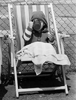 Young child swigs from a mug of juice, whilst sitting on a deck chair